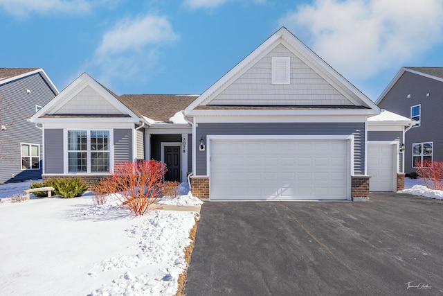 craftsman inspired home featuring an attached garage, driveway, and brick siding