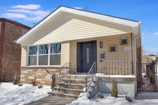 view of front of property featuring covered porch, stone siding, and brick siding