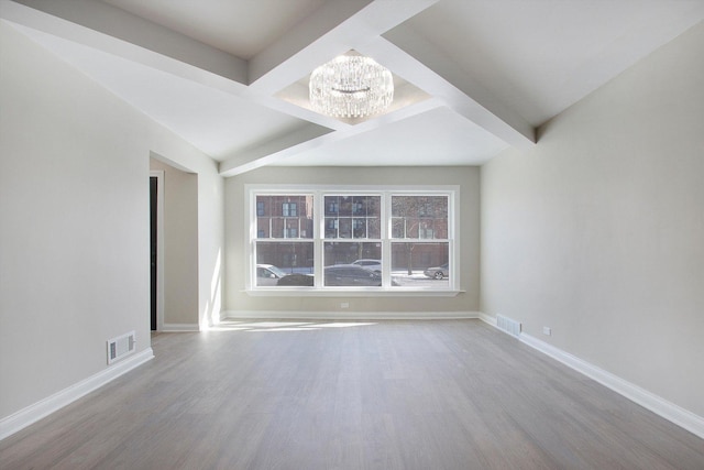 unfurnished room featuring baseboards, visible vents, a chandelier, and wood finished floors