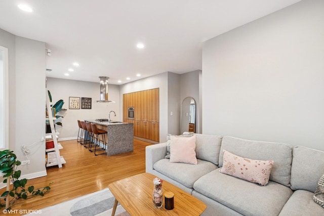 living area with baseboards, light wood finished floors, and recessed lighting