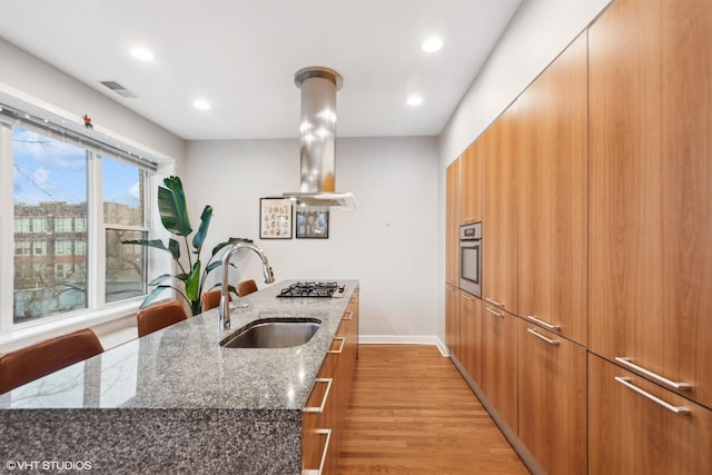 kitchen with island exhaust hood, visible vents, appliances with stainless steel finishes, a sink, and modern cabinets