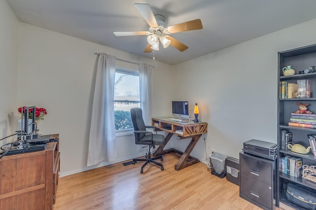 office space featuring baseboards, a ceiling fan, and light wood finished floors