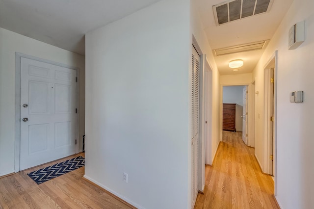 corridor featuring attic access, light wood-style floors, and visible vents