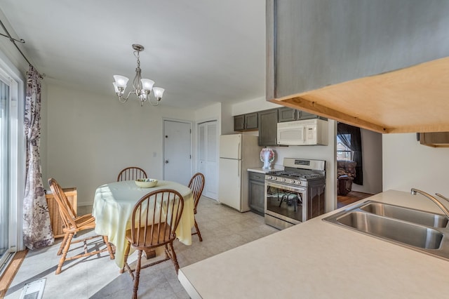 kitchen with visible vents, pendant lighting, a sink, white appliances, and light floors