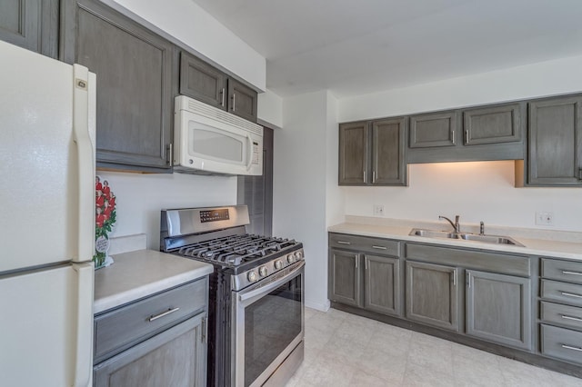 kitchen with a sink, white appliances, and light countertops