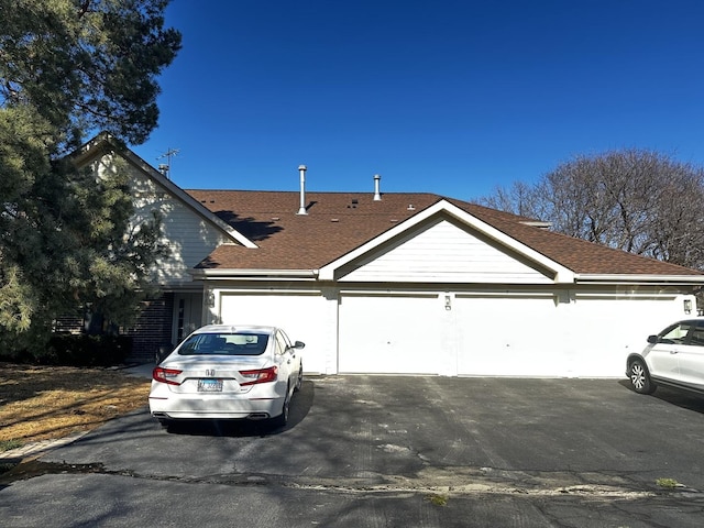 view of front of home with a garage and roof with shingles