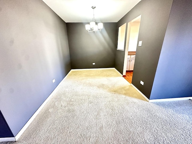 empty room featuring light colored carpet, a notable chandelier, and baseboards