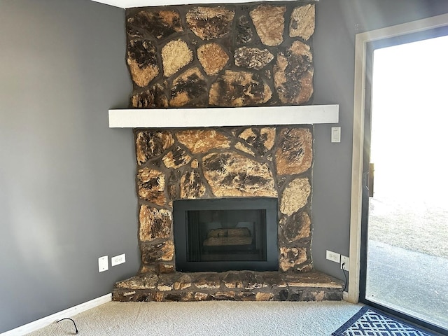 details featuring carpet flooring, a stone fireplace, and baseboards