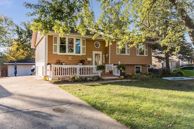 raised ranch with covered porch, a front lawn, an outdoor structure, and a garage