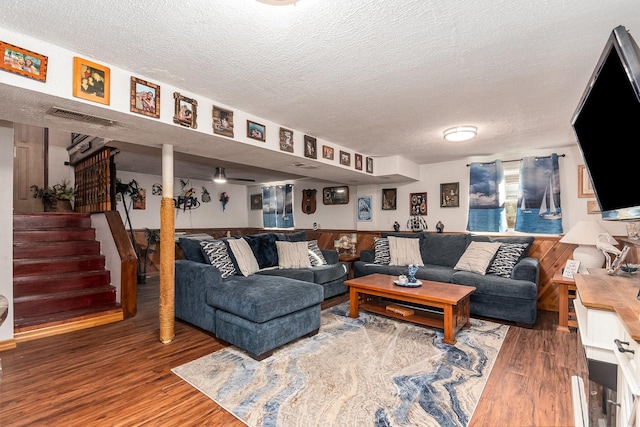 living area with stairs, visible vents, a textured ceiling, and wood finished floors