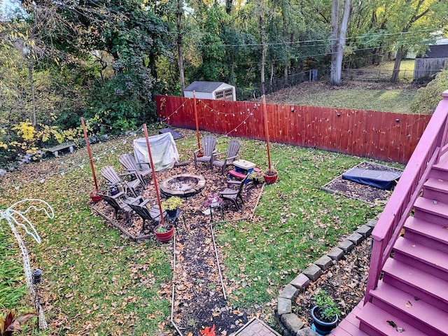 view of yard with an outdoor fire pit, a fenced backyard, and stairs