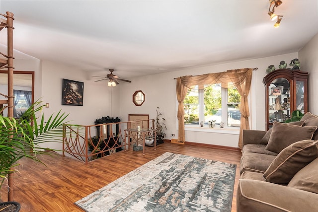 living area featuring a ceiling fan, baseboards, and wood finished floors