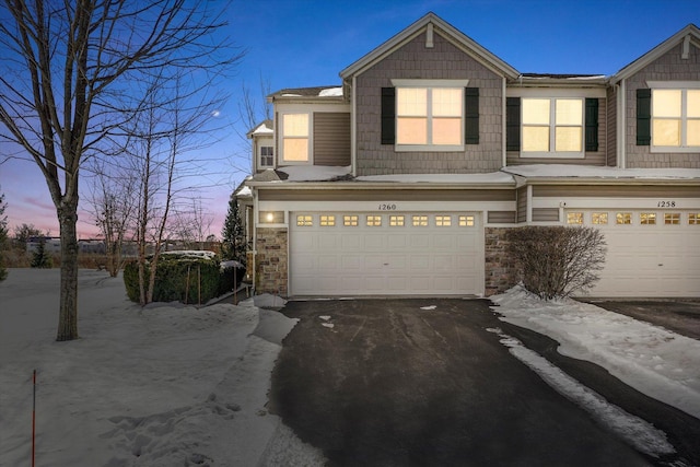 view of front of home featuring stone siding, aphalt driveway, and an attached garage