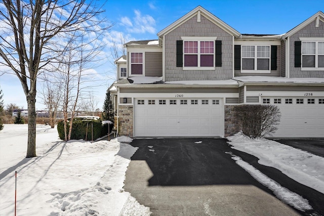 view of front of house with driveway, stone siding, and an attached garage