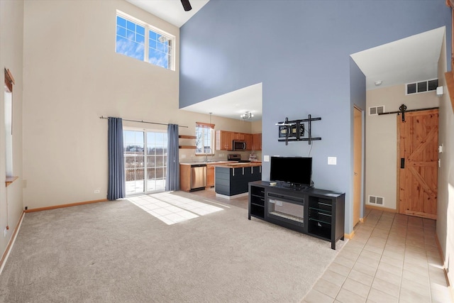 living area with a barn door, visible vents, and light colored carpet