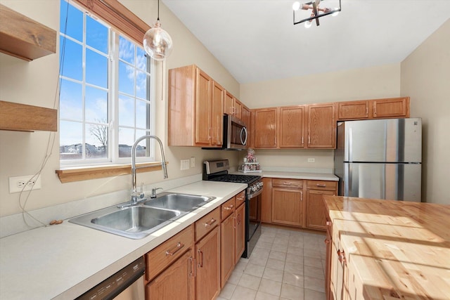 kitchen with decorative light fixtures, light tile patterned floors, stainless steel appliances, a sink, and wood counters