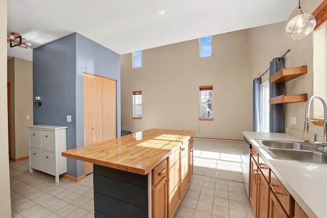 kitchen with butcher block counters, a kitchen island, a sink, dishwasher, and pendant lighting