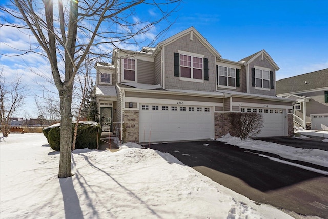 view of front of house with driveway, stone siding, and an attached garage