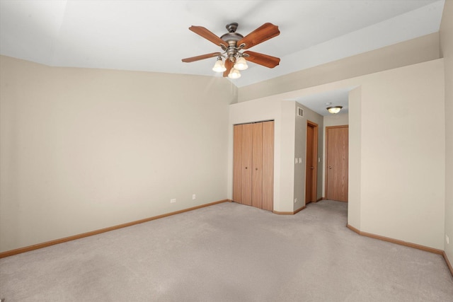 unfurnished bedroom with a closet, light colored carpet, a ceiling fan, vaulted ceiling, and baseboards