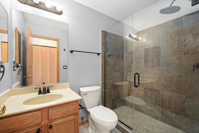 bathroom with a shower stall, toilet, and vanity