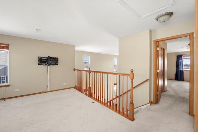 hallway with light carpet, baseboards, and an upstairs landing