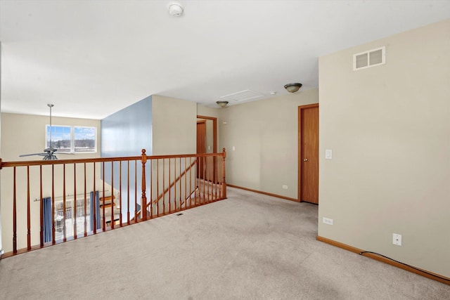 spare room with light carpet, a ceiling fan, visible vents, and baseboards