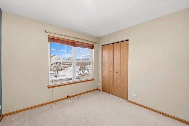 unfurnished bedroom with baseboards, a closet, visible vents, and light colored carpet