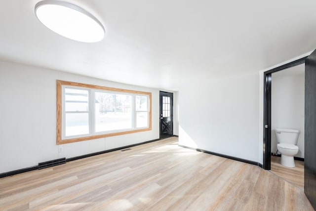 unfurnished room featuring wood finished floors, visible vents, and baseboards