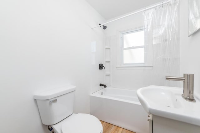 bathroom featuring toilet, vanity, wood finished floors, and shower / bathtub combination