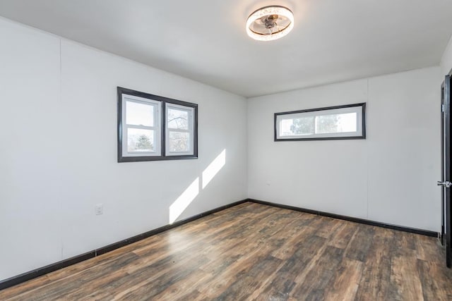 unfurnished room with dark wood-style floors and baseboards