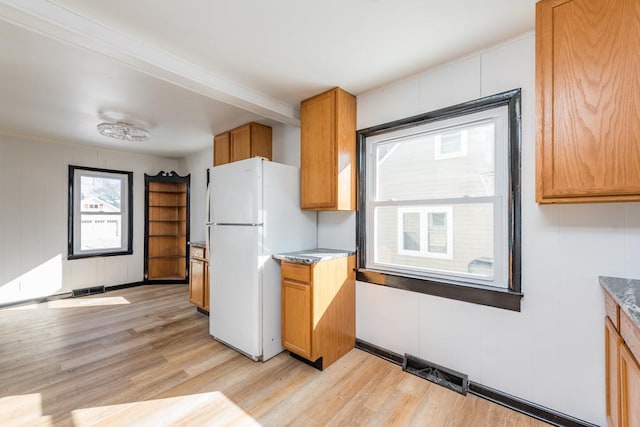 kitchen featuring brown cabinets, freestanding refrigerator, visible vents, and light wood-style flooring