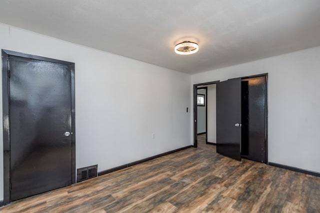 unfurnished bedroom featuring baseboards, visible vents, and dark wood finished floors