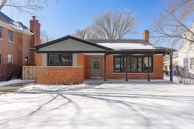 view of front facade with brick siding, fence, and a chimney