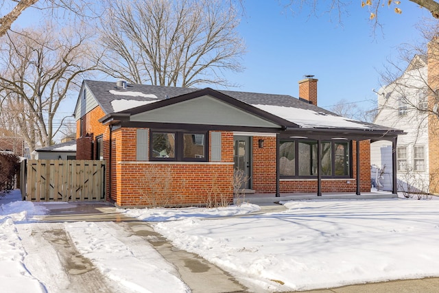 view of front facade with brick siding, fence, and a chimney