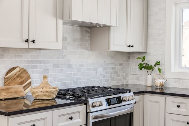 kitchen with dark countertops, gas range, tasteful backsplash, and white cabinetry