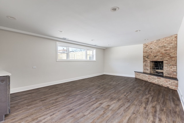 unfurnished living room with a fireplace, dark wood finished floors, visible vents, and baseboards