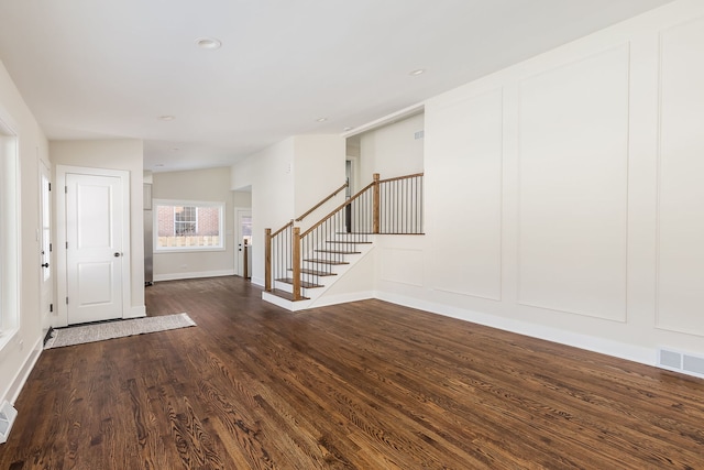 entryway featuring dark wood finished floors, visible vents, a decorative wall, baseboards, and stairs