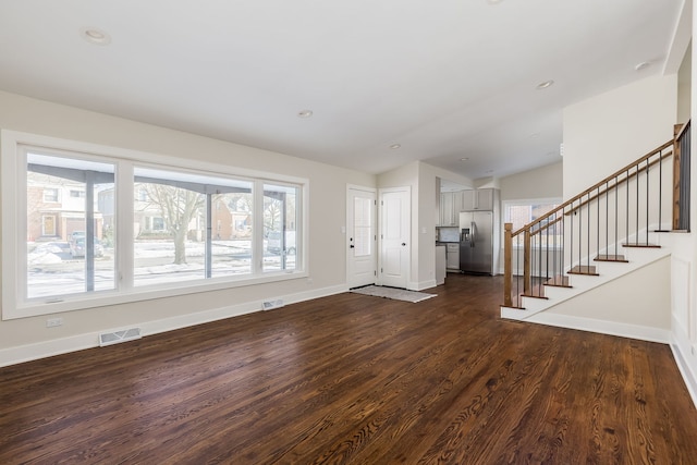 foyer featuring a healthy amount of sunlight, stairs, visible vents, and dark wood finished floors