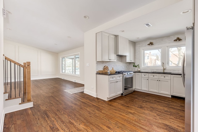 kitchen featuring visible vents, white cabinets, dark countertops, stainless steel appliances, and a sink