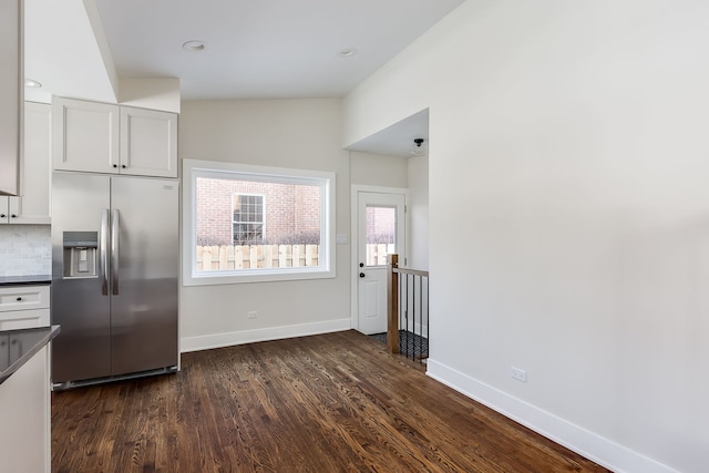 kitchen featuring baseboards, white cabinets, stainless steel fridge with ice dispenser, dark countertops, and dark wood-type flooring