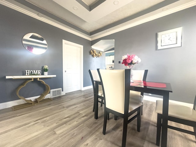 dining area with crown molding, visible vents, baseboards, and wood finished floors