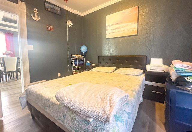 bedroom with ornamental molding and wood finished floors