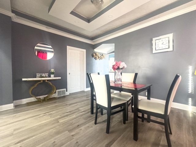 dining room featuring ornamental molding, visible vents, baseboards, and wood finished floors