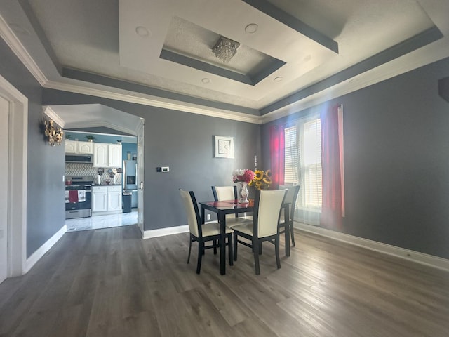 dining space with dark wood-style floors, baseboards, a raised ceiling, and ornamental molding