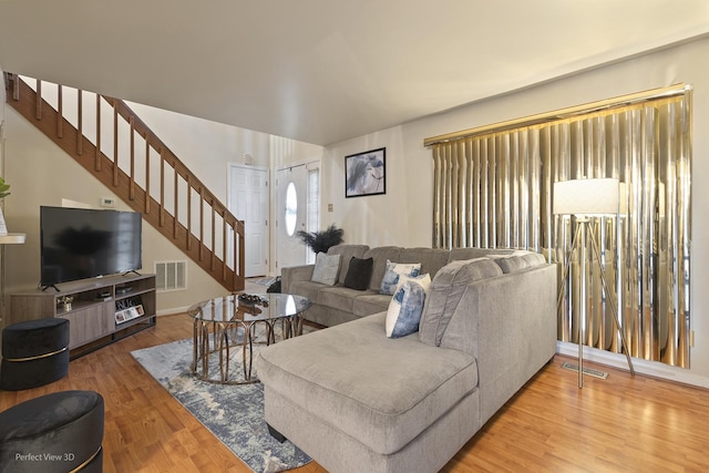 living area with stairway, wood finished floors, and visible vents