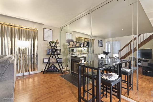 dining room with a fireplace with flush hearth, visible vents, wood finished floors, and stairs