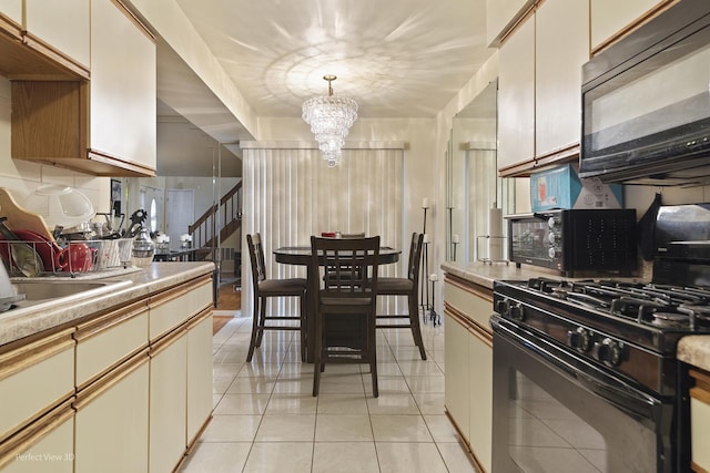 kitchen featuring light tile patterned floors, light countertops, black appliances, pendant lighting, and a notable chandelier