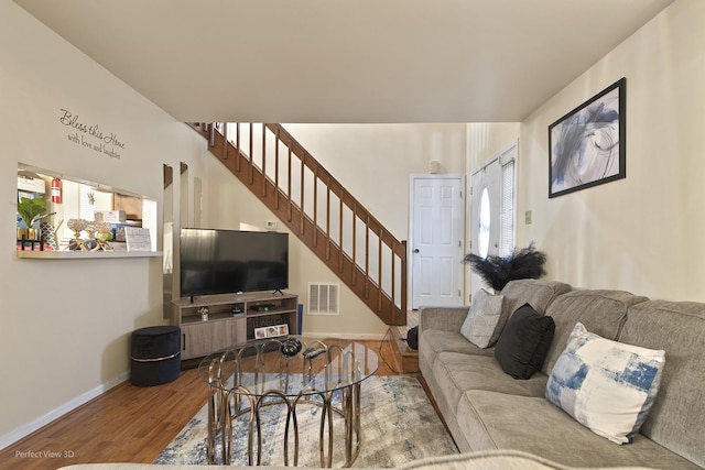 living room featuring baseboards, stairs, visible vents, and wood finished floors