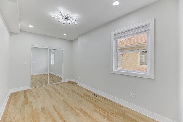 unfurnished bedroom featuring recessed lighting, a closet, light wood-style flooring, and baseboards