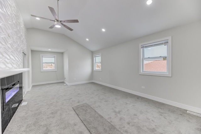 unfurnished living room featuring lofted ceiling, light carpet, visible vents, baseboards, and a glass covered fireplace